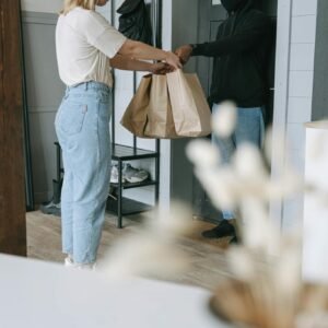 Man in White Shirt and Blue Denim Jeans Holding Brown Paper Bag