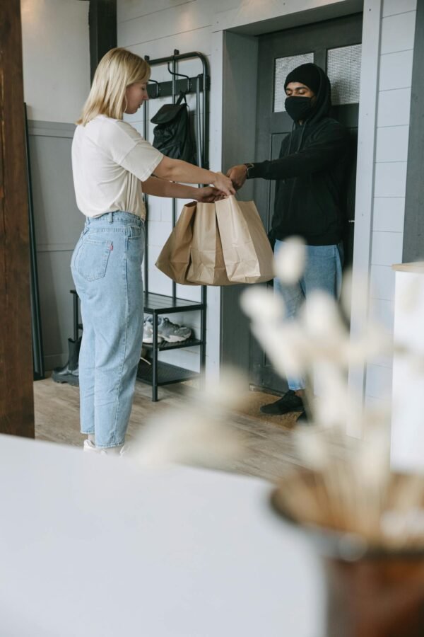 Man in White Shirt and Blue Denim Jeans Holding Brown Paper Bag